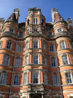 an old building with many windows and balconies on the top floor, in front of a blue sky