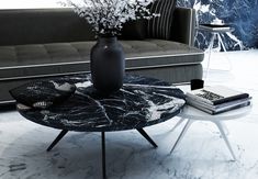 a black and white marble coffee table with flowers in a vase next to a couch