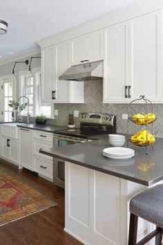 a kitchen with white cabinets and black counter tops, along with an area rug on the floor