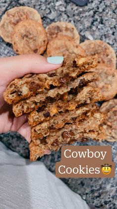 cowboy cookies are stacked in the palm of someone's hand with text overlay