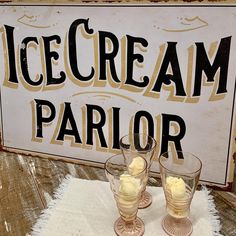 two glasses filled with ice cream sitting on top of a white towel next to a sign