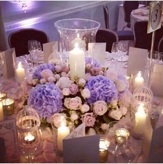 a centerpiece with flowers and candles on a table