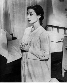 an old black and white photo of a woman standing in a bedroom