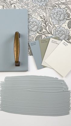 some paint swatches are sitting on a table next to a wallpaper with flowers