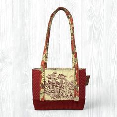 This medium, hand-sewn Cream & Maroon Tote Bag is perfect for carrying your items to school, work, church, shopping, or travel. It also makes a great gift! ★ Features: * Convenient Design: With no zippers or snaps, this tote bag is easy to throw on and go! * Travel-Friendly: Collapsible design allows for travel and saving space. * Eco-Friendly: Made from upcycled fabrics, this tote is a sustainable choice for the environmentally conscious. * Stylish and Durable: Fully lined with coordinating fabric for added durability and a polished look. ★ Details: * Size: 12" width x 9" height x 3.5" depth x 27.75" strap length * Pockets: 3 interior pockets for easy organization * Primary Colors: Maroon, Cream Please note that image colors may differ in person due to variations in devices and screens. Rectangular Satchel For School, Red Square Satchel For School, Square Shoulder Bag With Handles For School, Rectangular School Bag With Cell Phone Pocket, Medium Shoulder Bag For Daily Use, Square School Bags With Handles, Daily Use Fabric Satchel Shoulder Bag, Brown Fabric Bags For Everyday Use, Fabric Tote Satchel For Daily Use