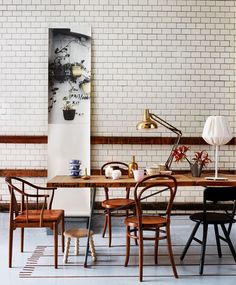 a dining room table with chairs and a lamp on top of it next to a white brick wall