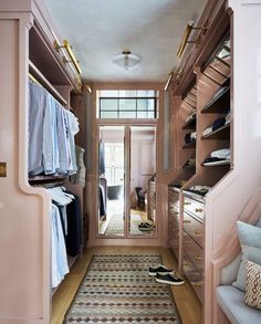 a walk - in closet with pink walls and wooden shelves filled with clothes, shoes and other items