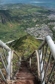 stairs leading down to the top of a hill with a view of town below and ocean in the distance