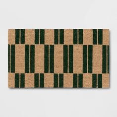 a door mat with green and brown stripes on the front, against a white wall