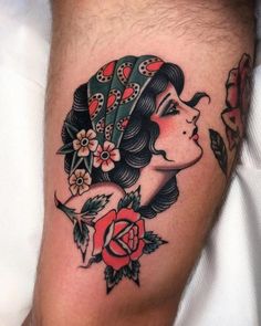 a woman's face with flowers and leaves on her leg, done by tattoo artist