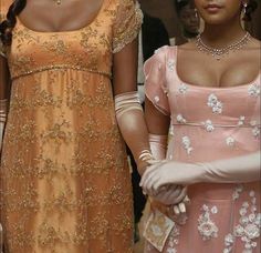 two women dressed in evening gowns standing next to each other and one wearing gloves