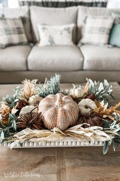 a living room with a couch, coffee table and white pumpkins on the centerpiece