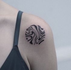 a woman's shoulder with a black and white tattoo design on her left arm