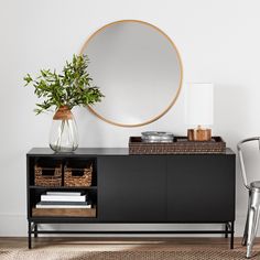 a black sideboard with a round mirror above it