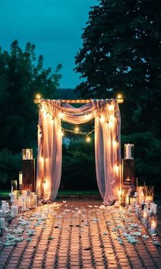 an outdoor wedding set up with candles and draping on the ground at night