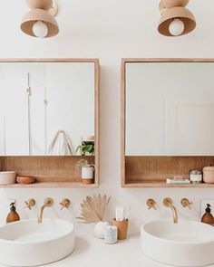 two sinks in a bathroom with mirrors and lights on the wall above them, next to each other