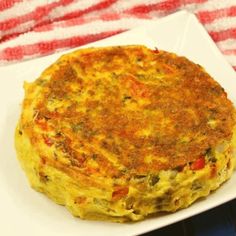 an omelet on a white plate with a red and white striped table cloth