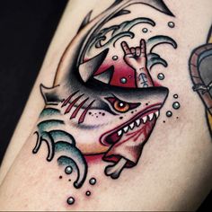 a close up of a person's arm with a shark and fish tattoo on it