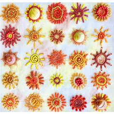 an assortment of beaded sunbursts are displayed on a white cloth background