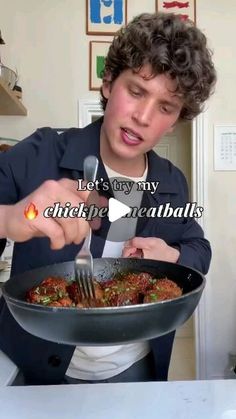 a young man holding a frying pan filled with food