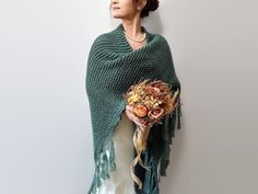 a woman wearing a green shawl and holding a bouquet of flowers in her hands