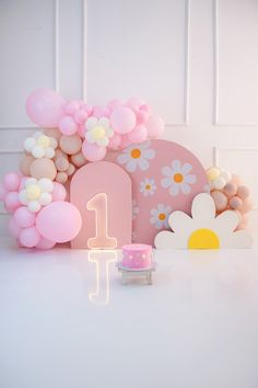 a table topped with balloons and flowers next to a cake