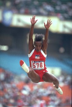 a woman jumping in the air on top of a long jump