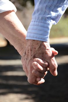 an older person holding the hand of a younger person