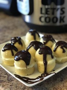 small desserts with chocolate drizzled on them sitting on a white plate