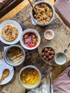 an assortment of food is displayed on a table with bowls and utensils around it