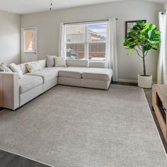 a living room with white furniture and a large gray rug on the floor in front of a window