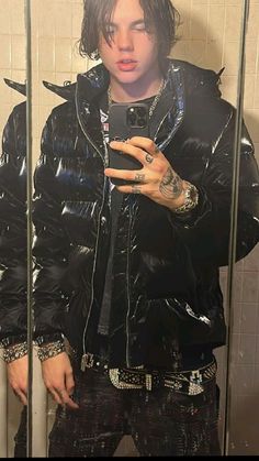 a man taking a selfie in front of a mirror wearing a black jacket and jeans