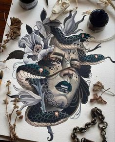 an artistic painting with flowers and snakes on it's face, surrounded by other art supplies