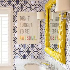 a bathroom with blue and white wallpaper has a sink, mirror, and window