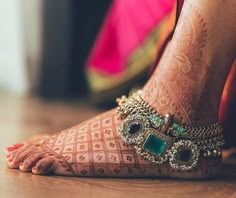 a woman's feet with hennap and jewels on them, sitting on the floor