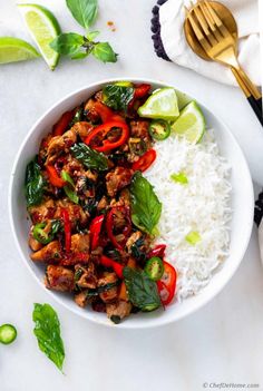 a white bowl filled with meat and vegetables next to rice on top of a table