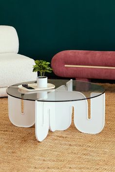 a glass table sitting on top of a wooden floor next to a white couch and chair