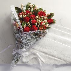 a bouquet of red roses wrapped in clear cellophane and tied with white ribbon