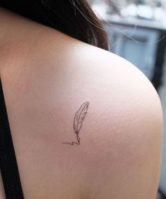 the back of a woman's shoulder with a small feather tattoo on her left arm