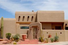 an adobe style house with cactus and cacti in front