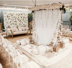 a wedding ceremony setup with white chairs and flowers on the back drop cloth draping