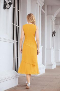 a woman in a yellow dress is walking down the sidewalk with her back to the camera