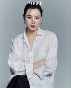 a woman sitting on the ground with her arms crossed, wearing a white shirt and black pants