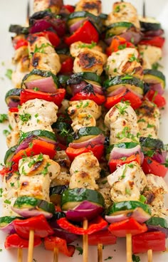 a white plate topped with chicken and veggie kabob skewers