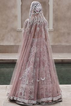 the back of a wedding dress with an elaborate veil on display in front of a building