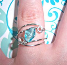 a woman's hand holding a ring with a blue topazte stone on it