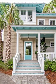 a house with palm trees in front of it and blue door on the side walk