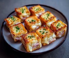 several pieces of bread with ham and cheese on it sitting on a plate next to a fork