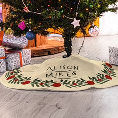 a decorated christmas tree with presents under it and a personalized sign on the bottom