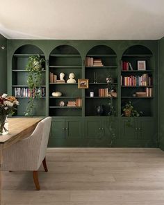 a dining room with green walls and built in bookshelves